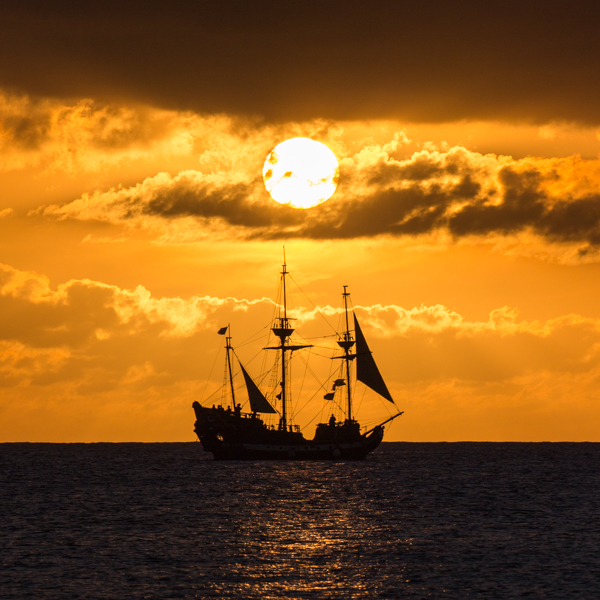 Photo of a pirate ship with the sun setting behind