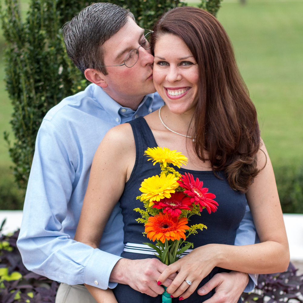 Photo of a couple, woman smiling and looking at camera while man kisses her